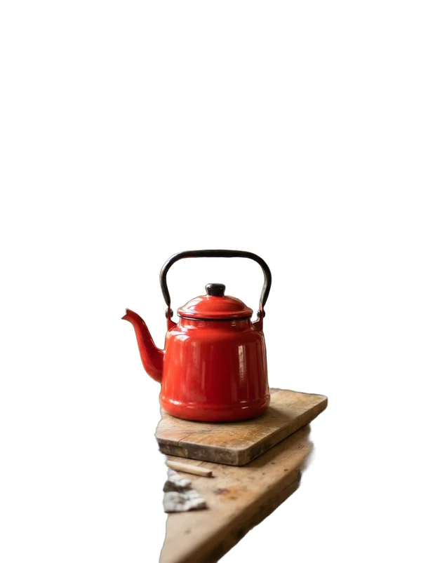 A red enamel teapot cut out from a cluttered kitchen counter